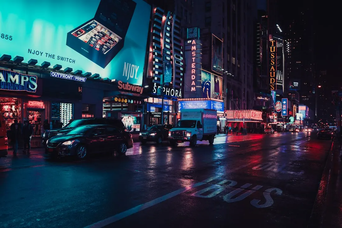 Billboards and neon signs over a wet city street at night