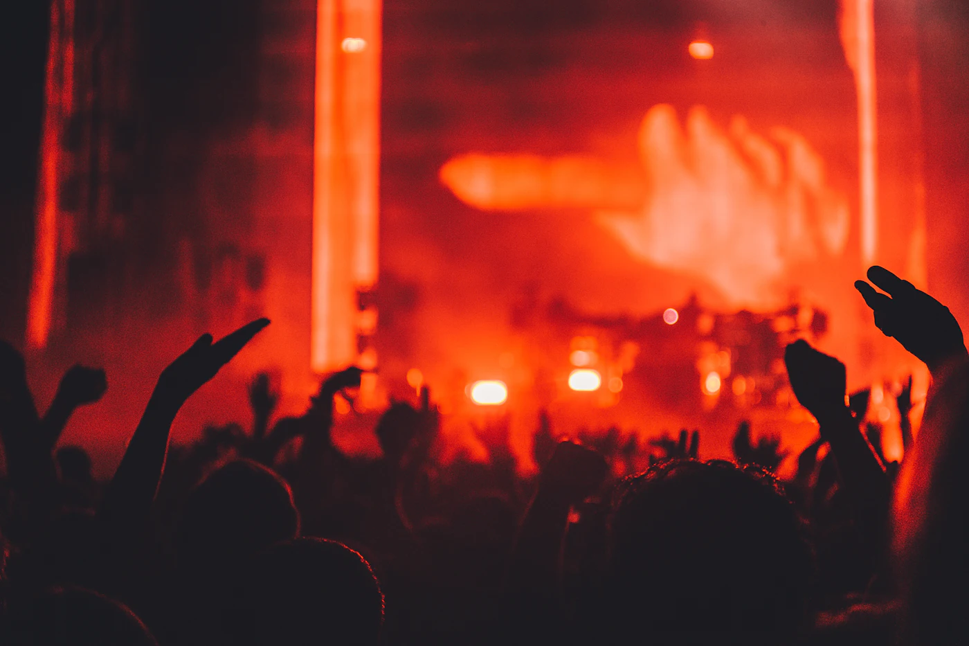 Concert crowd with hands raised under red light