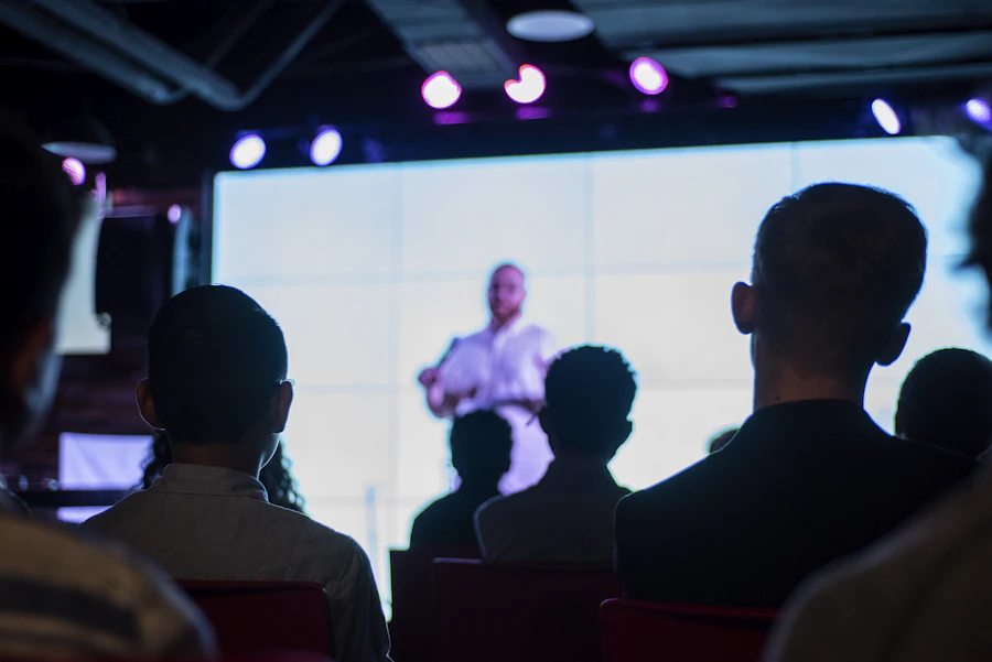 Audience facing a speaker and a large screen at a conference