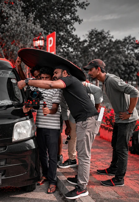 Crew holding a reflector over a camera operator filming into a car during one of our shoots