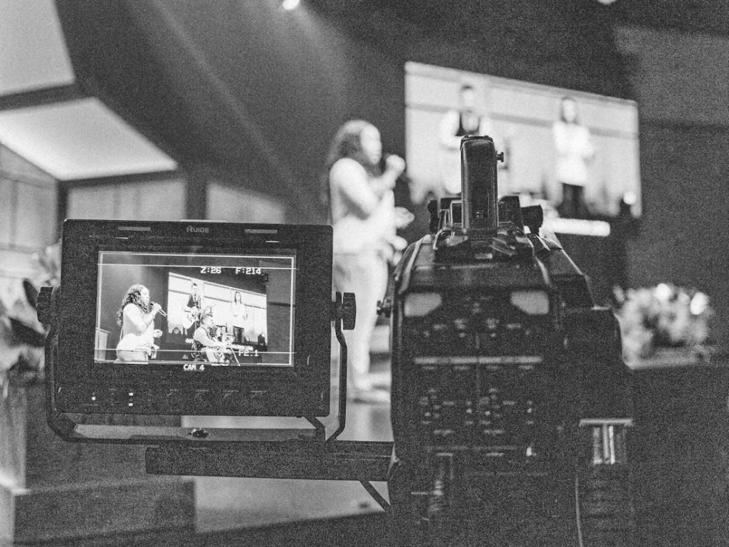 Black and white shot of a camera filming a presenter
